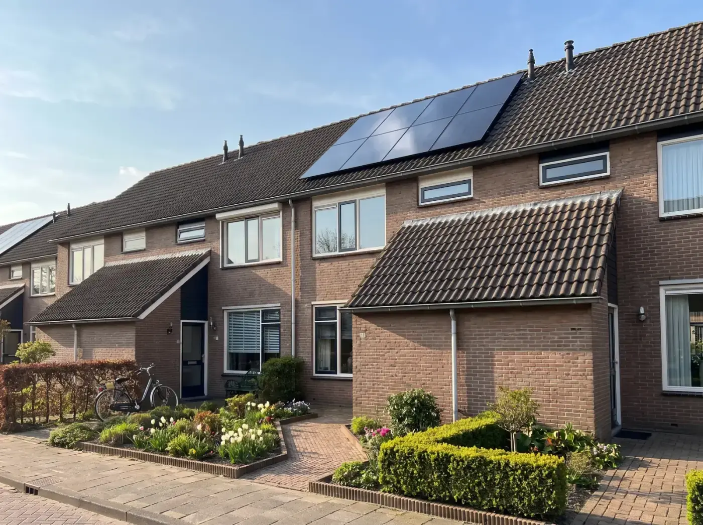 Rij Nederlandse rijtjeshuizen met zwarte zonnepanelen op het dak